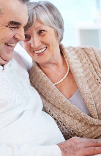 elderly woman smiling and leaning against elderly man