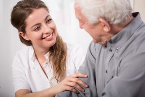 Smiling nurse at elderly man for senior care in Philadelphia.