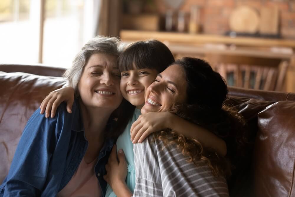 Three generations of women hugging on a couch