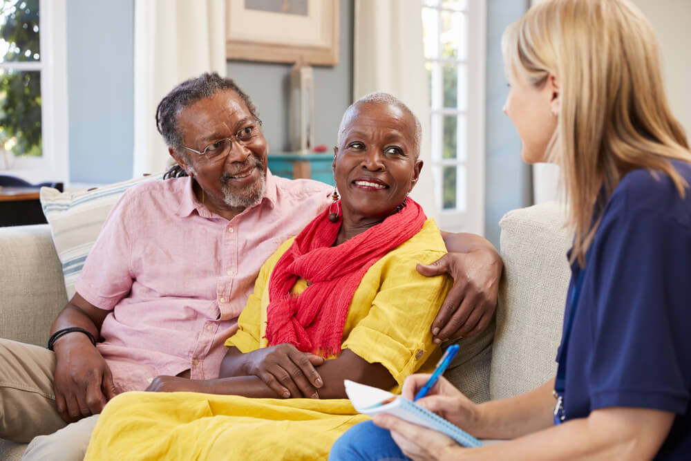 Patient advocate talking with senior couple on a couch