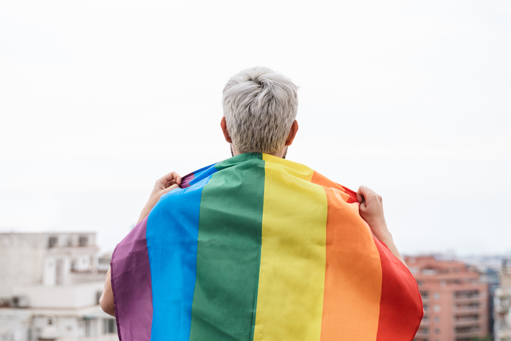 Elderly man with gray hair wrapped in rainbow pride flag